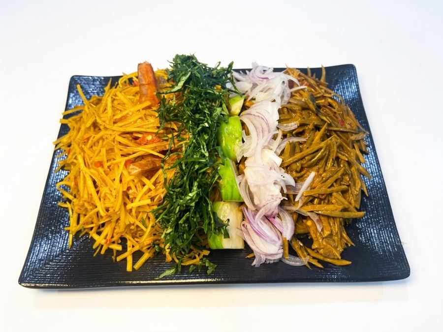 Abacha and ugba laid out on a black platter with utazi and onions