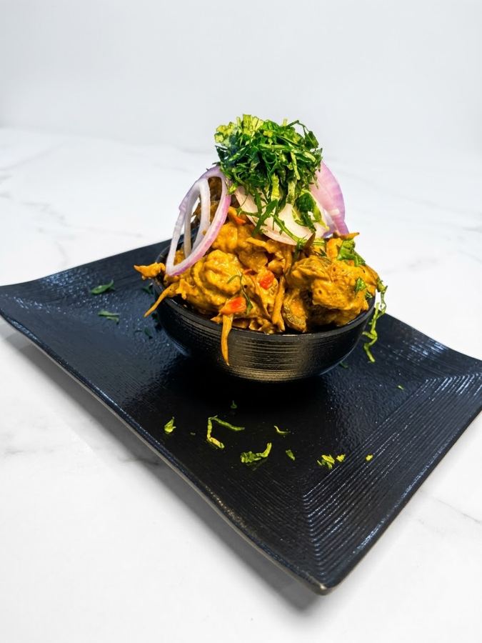 Isiewu piled high in a black bowl on a black plate