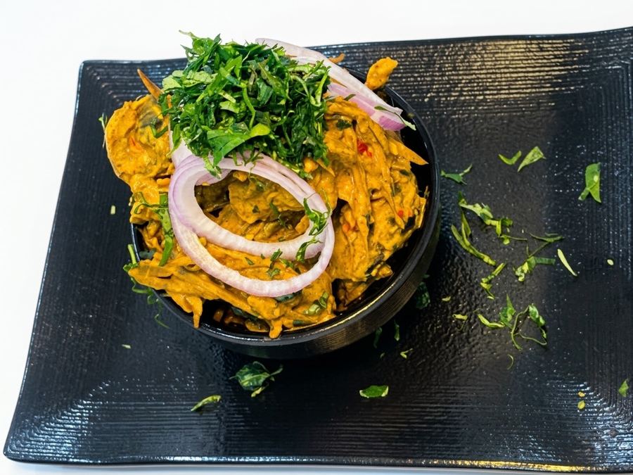Isiewu served in a black bowl on a black plate, seen from above