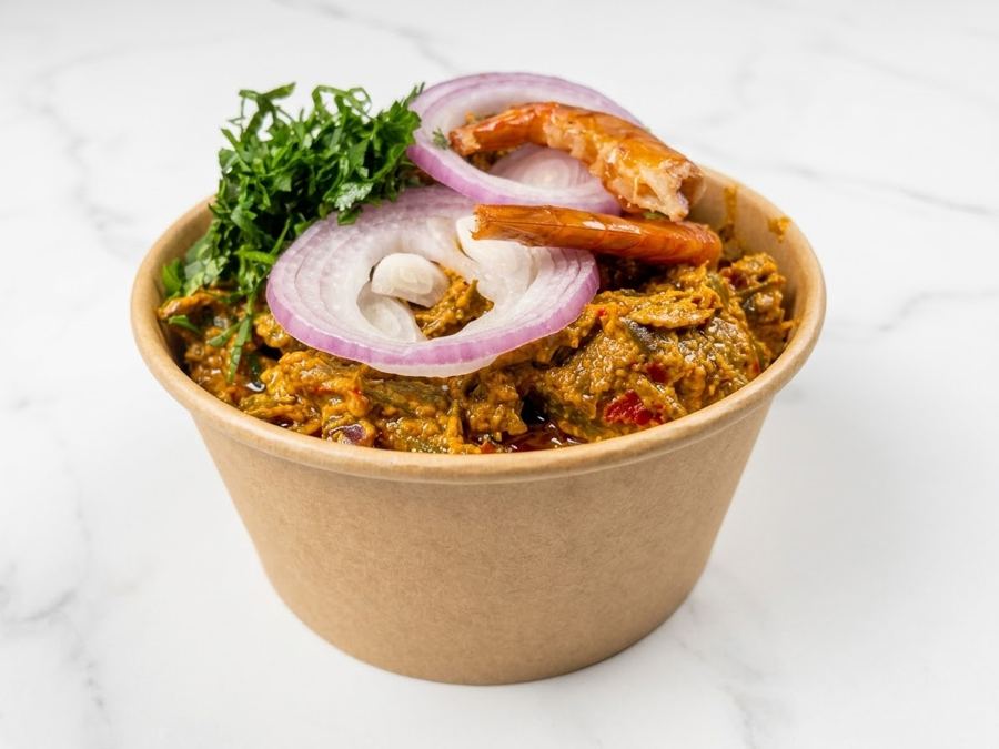 Isiewu in a kraft cup with onion rings and oporo
